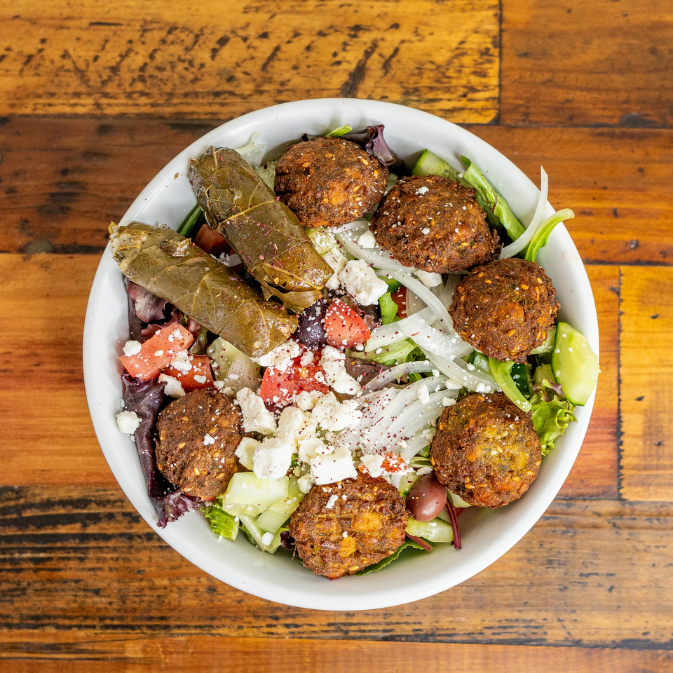 Mediterranean salad with falafel, stuffed grape leaves, feta, tomatoes, cucumbers, and onions.